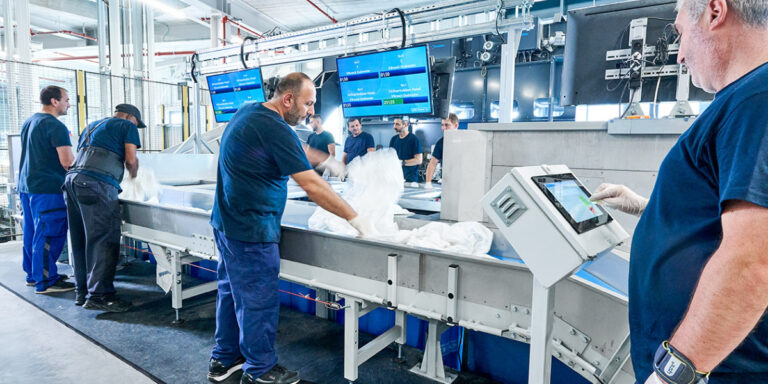 medewerkers laden vieze was op de transportband