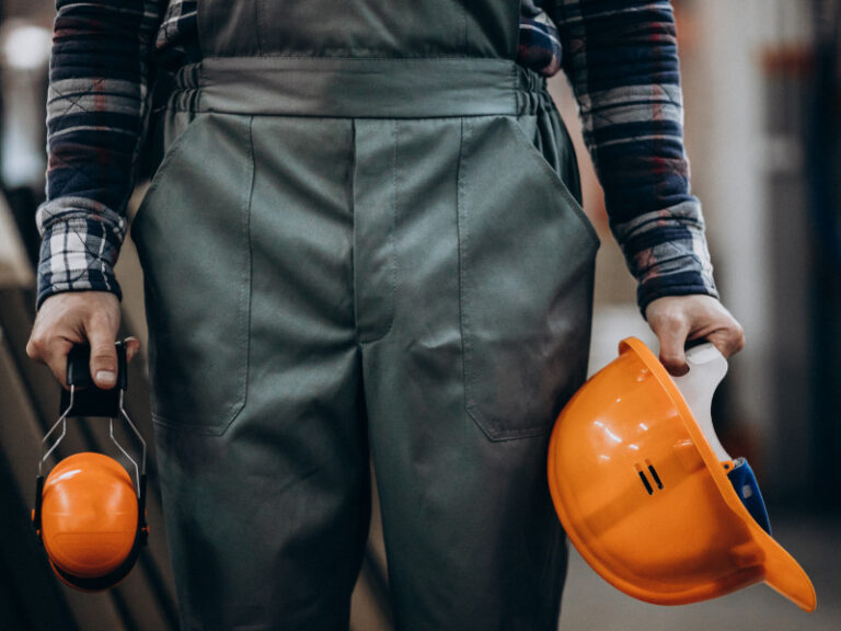 Werker met overall, helm en oorbeschermers