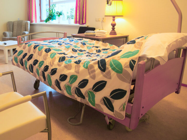 Kamer in verzorgingshuis met bed en dekbek op de voorgrond